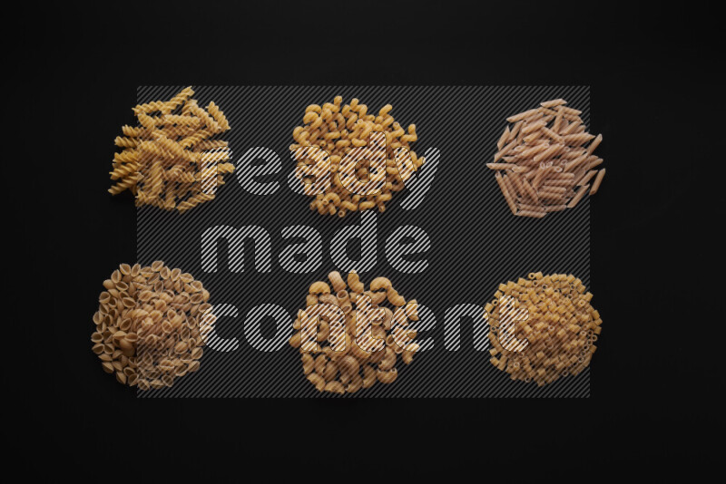 Different pasta types in bunches on black background