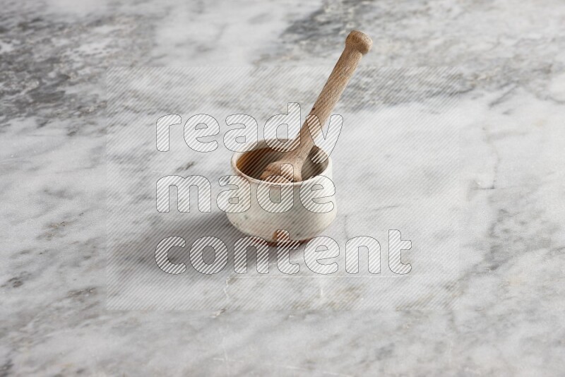 Beige pottery bowl with wooden honey dipper in it on grey marble background