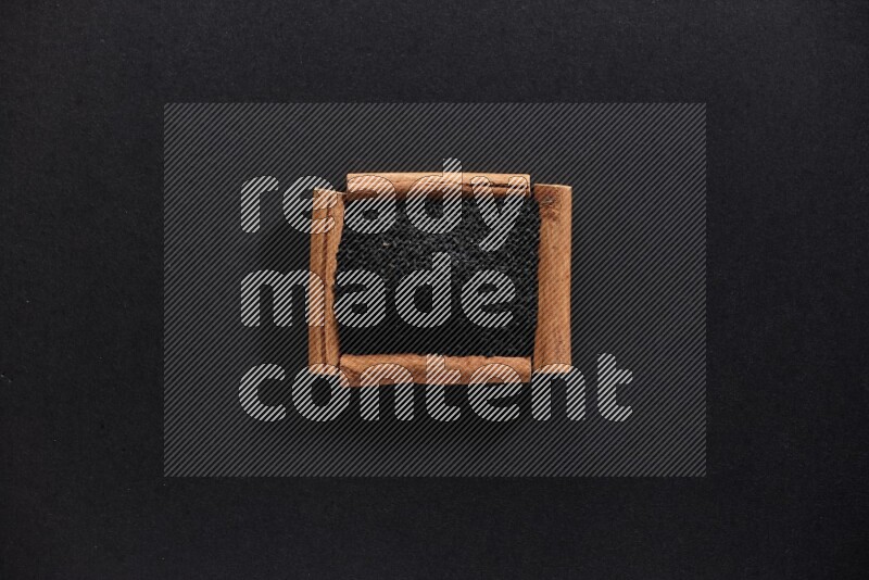 A single square of cinnamon sticks full of black seeds on black flooring