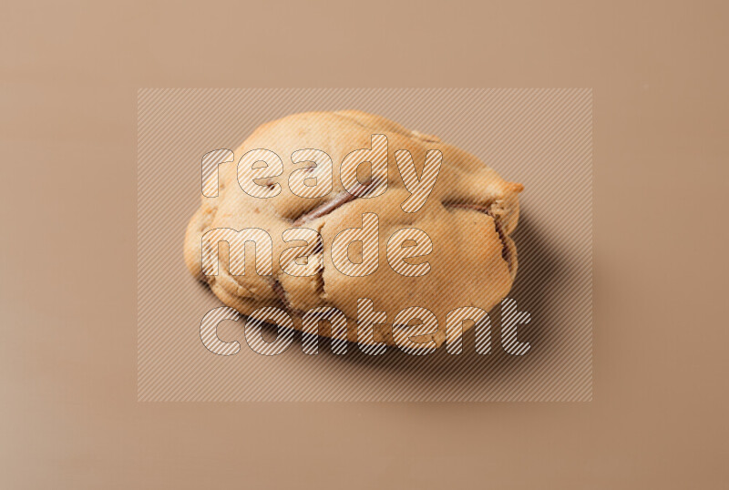 a whole chocolate chip cookie on a brown background