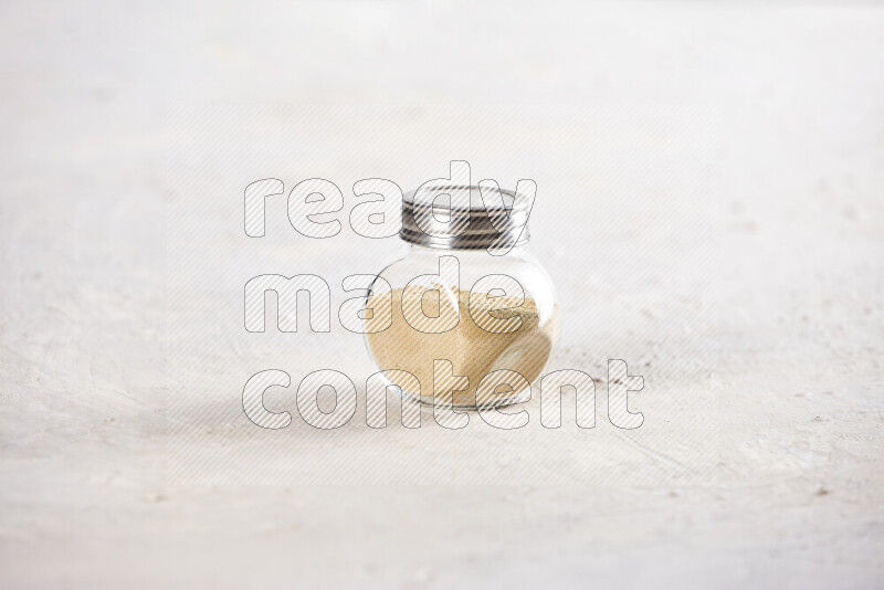 A glass jar full of ground ginger powder on white background