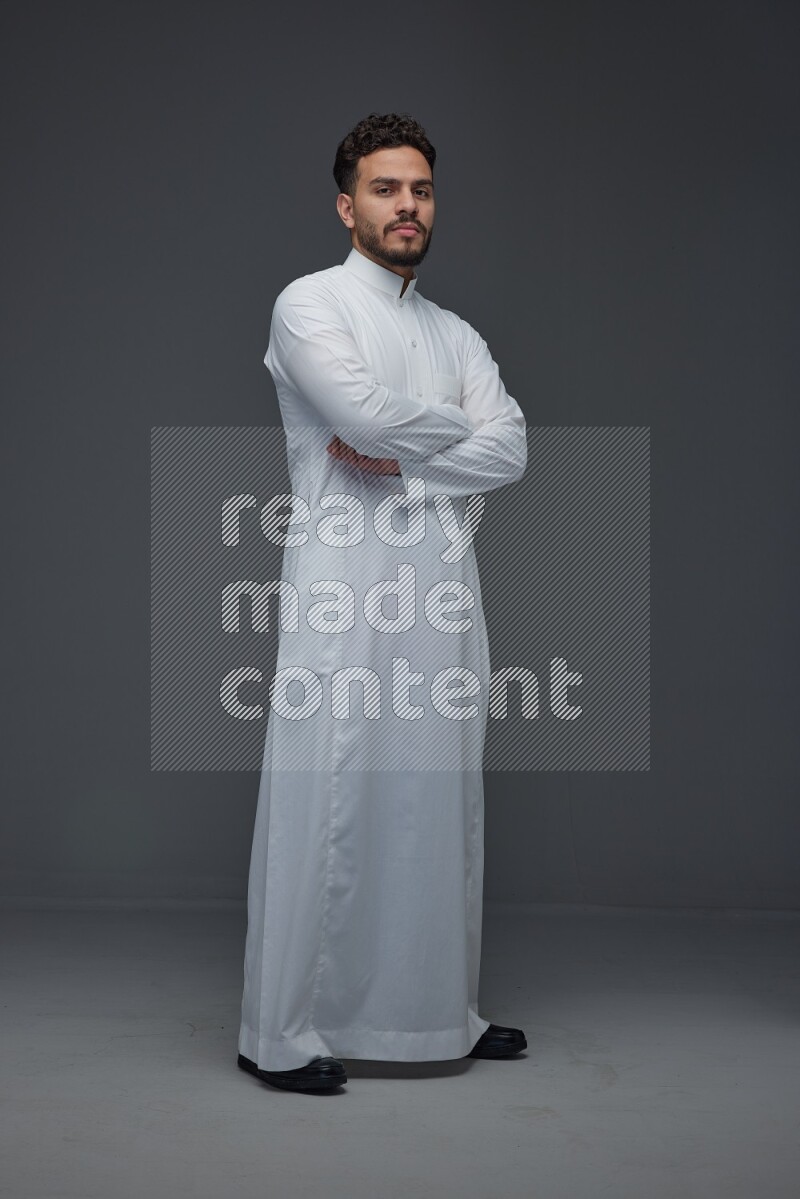 A Saudi man wearing Thobe standing and making different poses eye level on a gray background