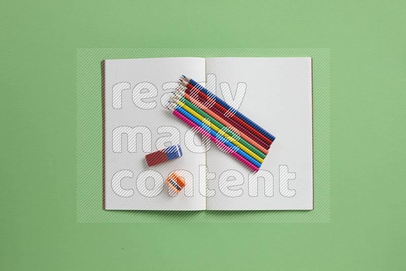 A blank open notebook with school supplies on green background (Back to school)