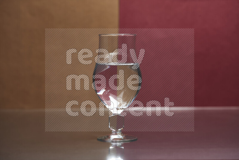 The image features a clear glassware filled with water, set against brown and dark red background