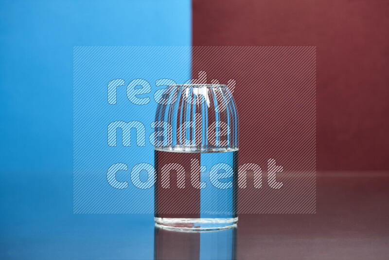 The image features a clear glassware filled with water, set against blue and dark red background