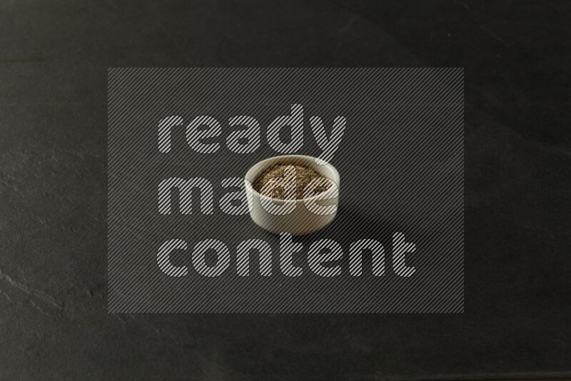 wooden round sauce bowl filled with herbs on grey textured countertop