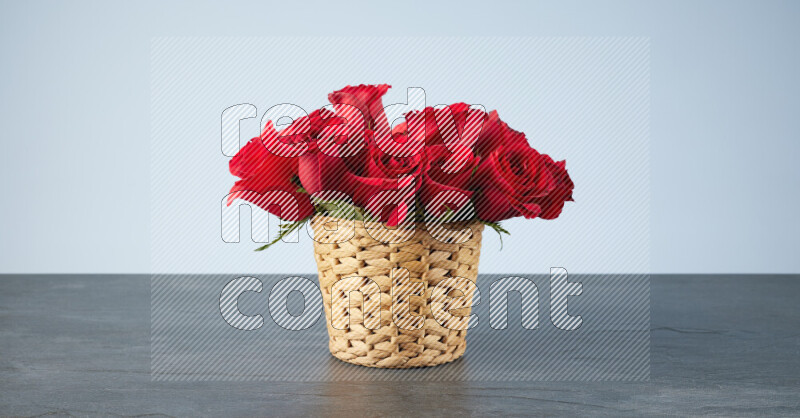 Vibrant red roses in a wicker basket on black marble background