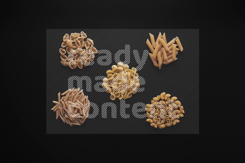 Different pasta types in bunches on black background