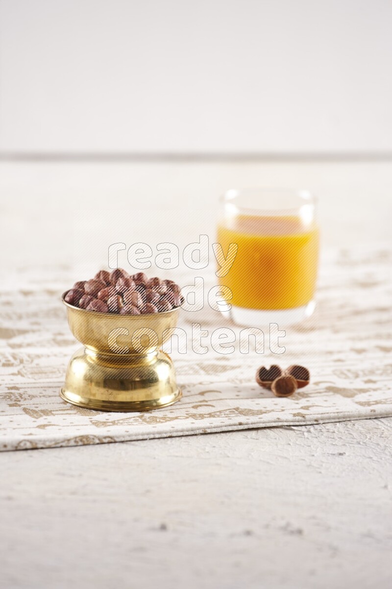 Nuts in a metal bowl with qamar eldin in a light setup