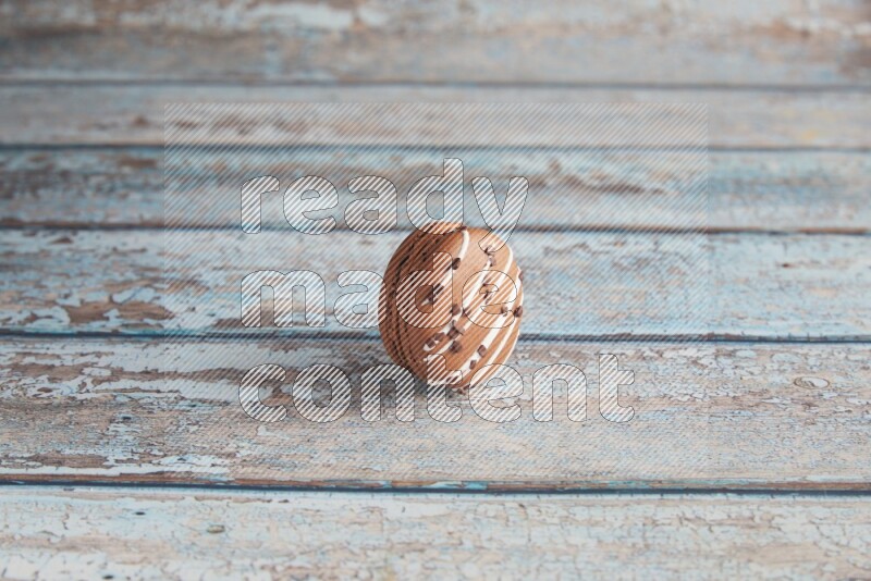45º Shot of Brown white Chocolate Caramel macaron on light blue wooden background
