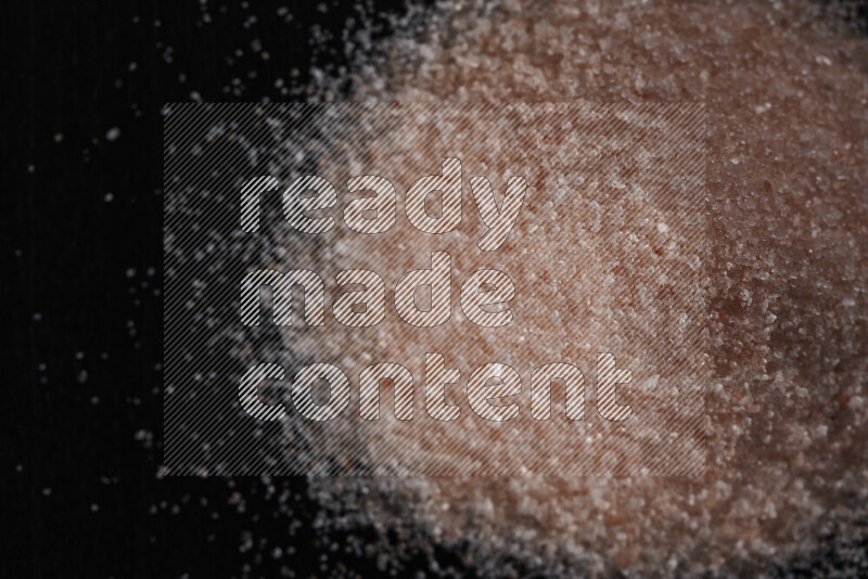 A bunch of fine himalayan pink salt on black background