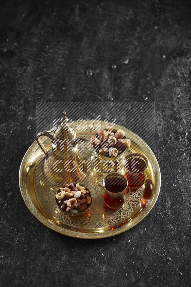 Nuts with dates and a drink on a metal tray in a dark setup