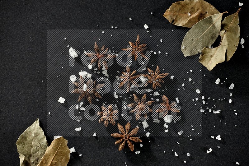 Salt, star anise and bay laurel on black flooring