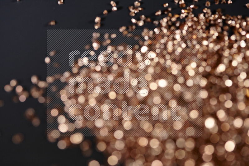 Bronze shimmering fragments of glass scattered on a black background