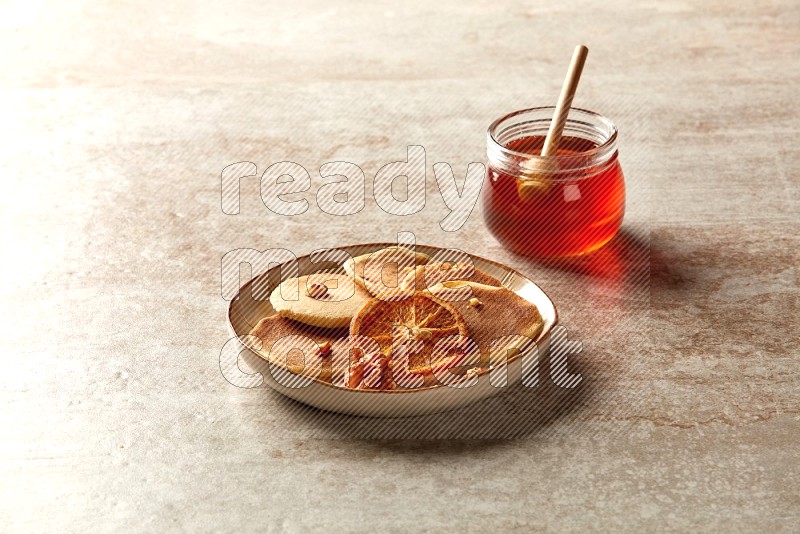 Five stacked dried orange mini pancakes in an irregular plate on beige background