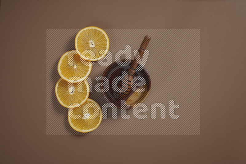 A bowl full of honey with some of citrus fruits such as lemon and orange on a beige background