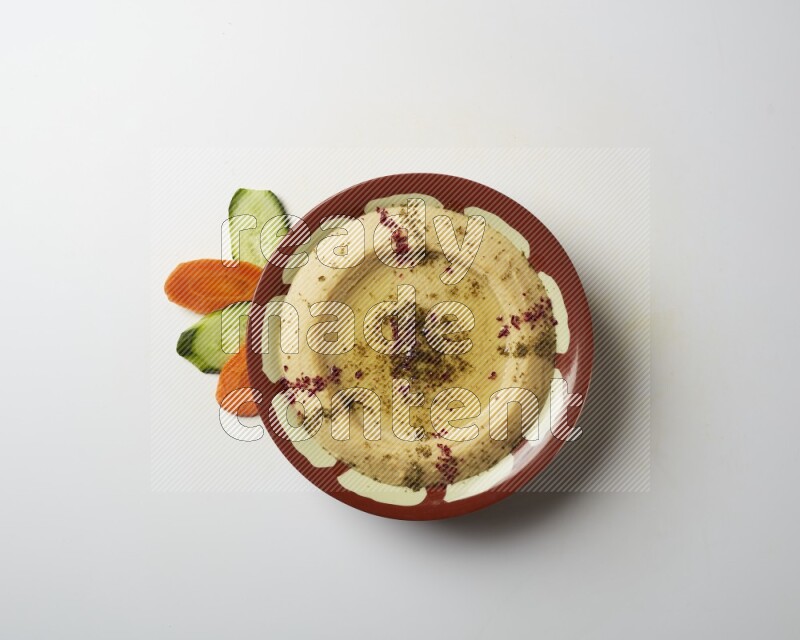 Hummus in a traditional plate garnished with zaatar & sumak on a white background