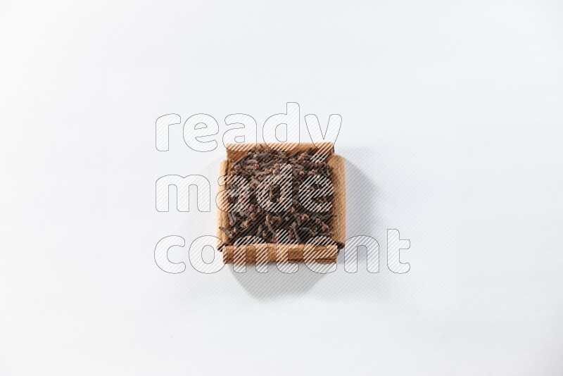 A single square of cinnamon sticks full of cloves on white flooring
