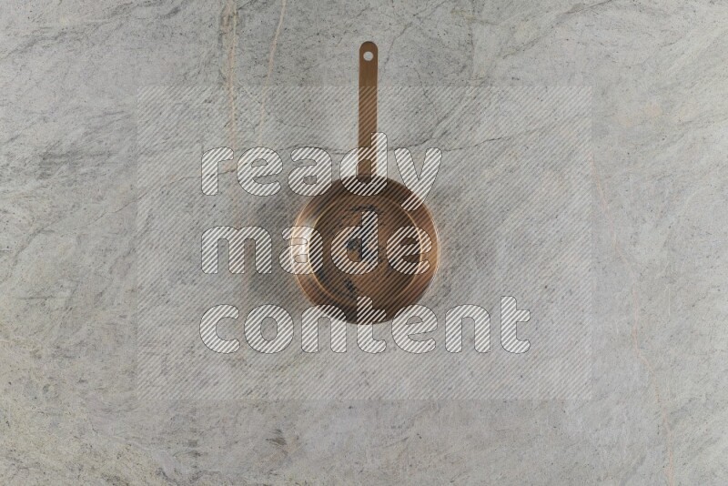 A small copper pan on grey marble background