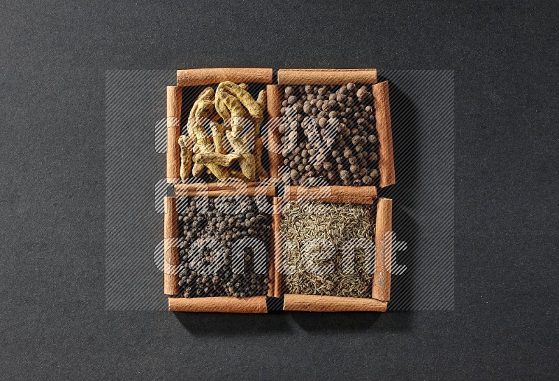 4 squares of cinnamon sticks full of black pepper, cumin, allspice and turmeric fingers on black flooring