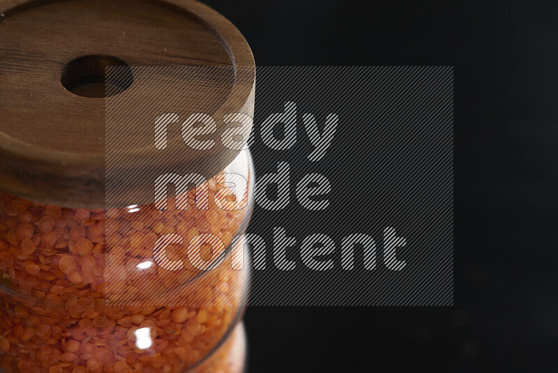 Lentils in a glass jar on black background