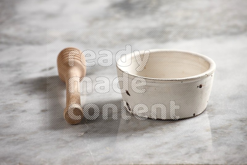 White Pottery Bowl with wooden honey handle on the side with grey marble flooring, 15 degree angle