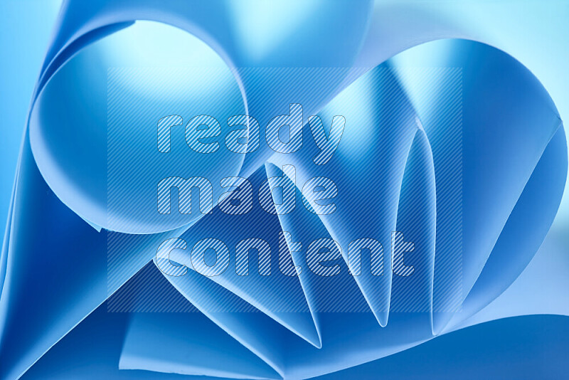 An artistic display of paper folds creating a harmonious blend of geometric shapes, highlighted by soft lighting in blue tones