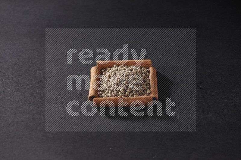 A single square of cinnamon sticks full of white pepper on black flooring