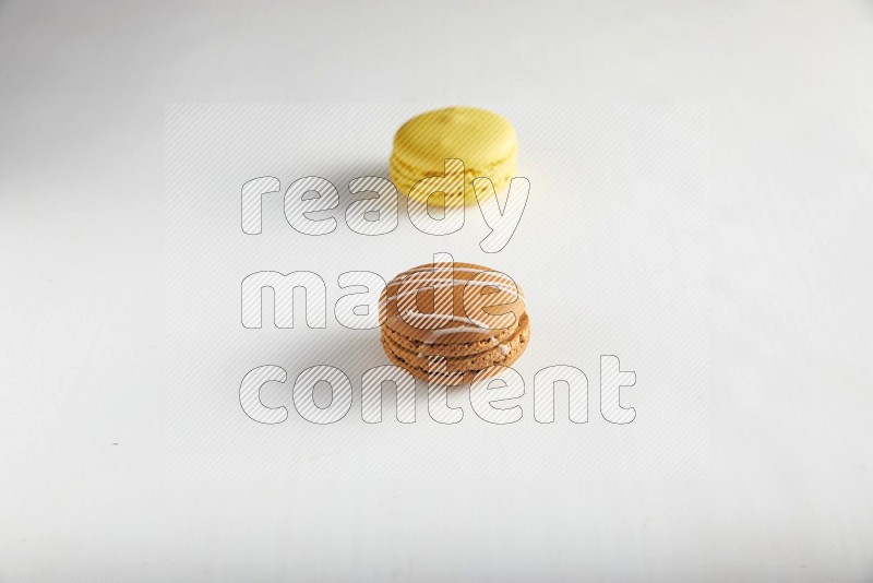 45º Shot of of two assorted Brown Irish Cream, and Yellow Lemon macarons on white background