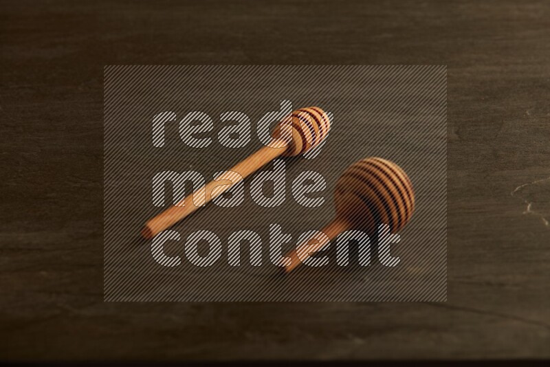 Wooden honey dipper on black slate background