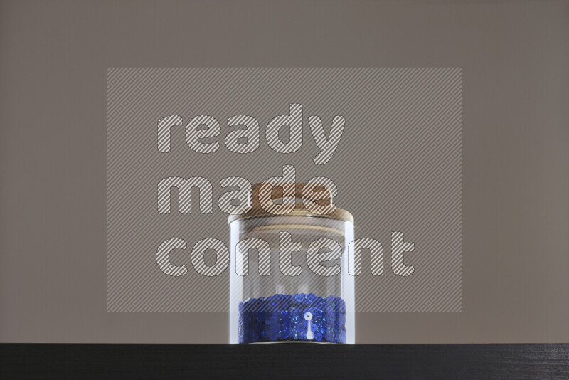 Sequins in a glass jar on black background