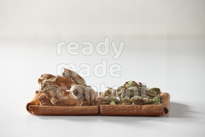 2 squares of cinnamon sticks full of cardamom and dried ginger on white flooring