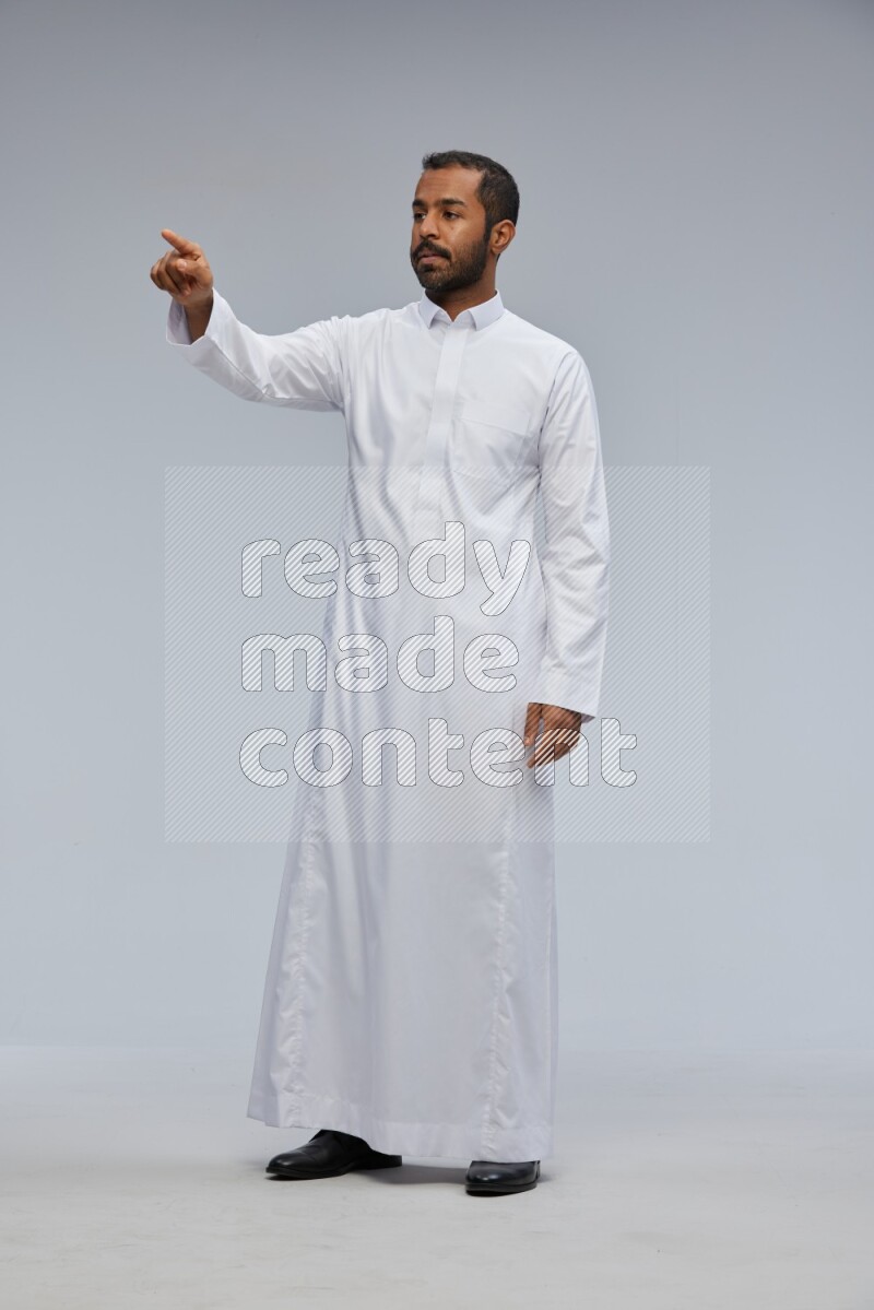 Saudi man Wearing Thob standing interacting with the camera on Gray background