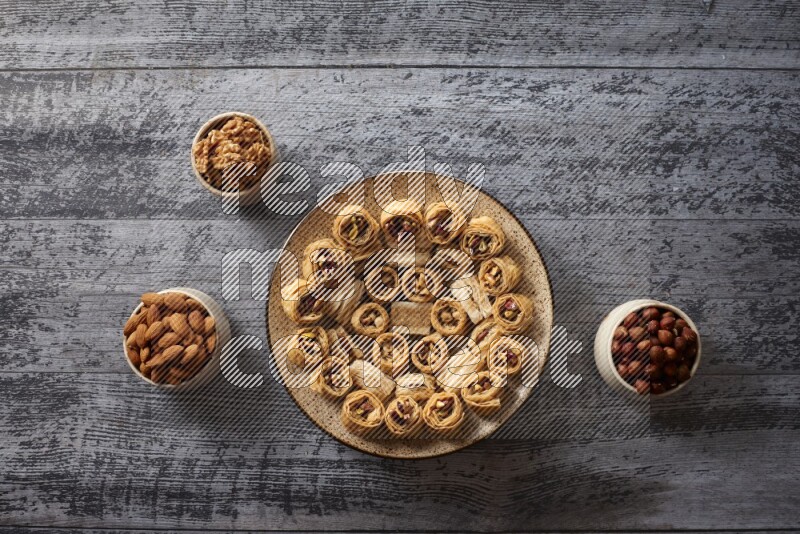 Oriental sweets in a pottery plate with nuts, coffee and honey in a dark setup