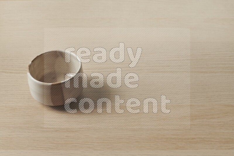 A beige pottery bowl on light wooden background