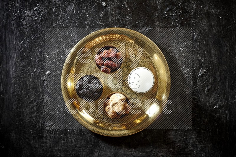 Dried fruits in metal bowls with sobya on a tray in dark setup