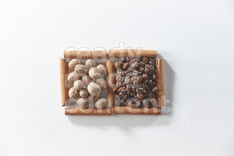 مربعان من أعواد القرفة ممتلئان بحبوب القهوة وجوزة الطيب علي خلفية بيضاء