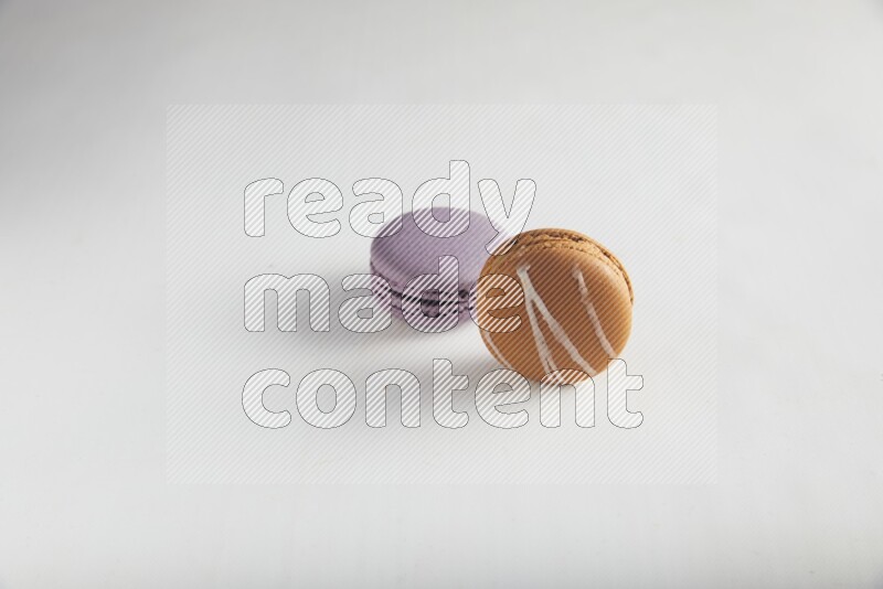 45º Shot of of two assorted Brown Irish Cream, and Purple Blueberry macarons on white background