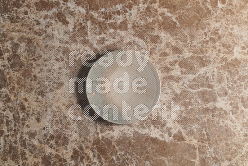 A multicolored pottery plate on beige marble background