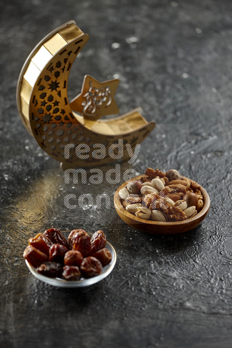 A crescent lantern with drinks, dates, nuts, prayer beads and quran on textured black background
