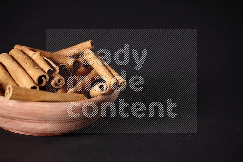 Cinnamon Sticks in a wooden bowl on black background