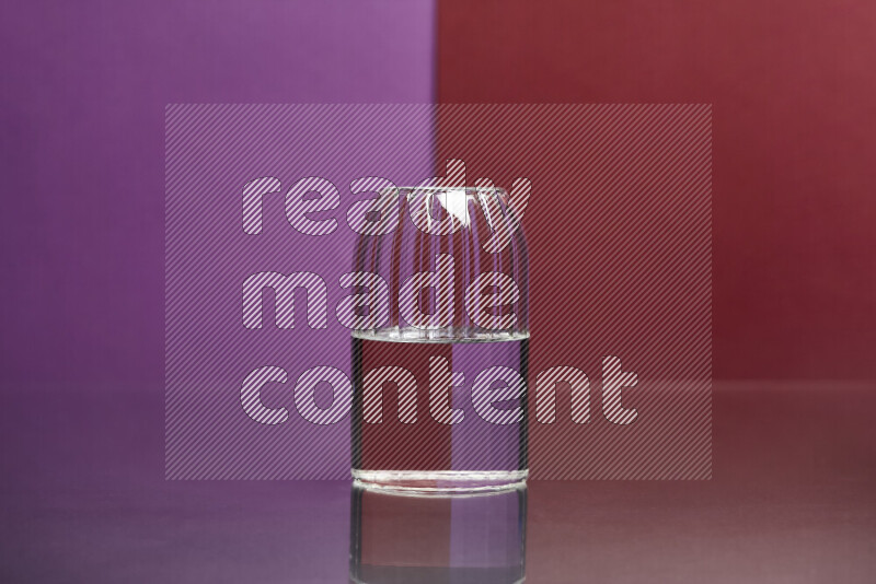 The image features a clear glassware filled with water, set against purple and dark red background