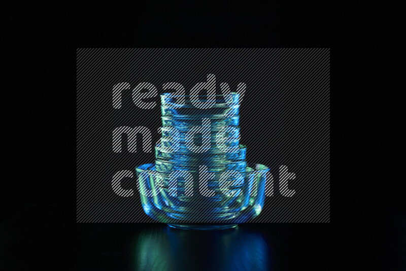 Glassware with rim light in blue and green against black background