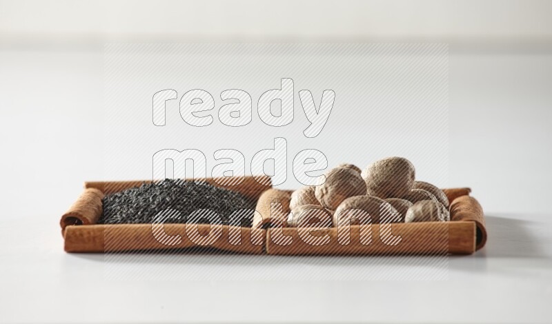 2 squares of cinnamon sticks full of black seeds and nutmeg on white flooring