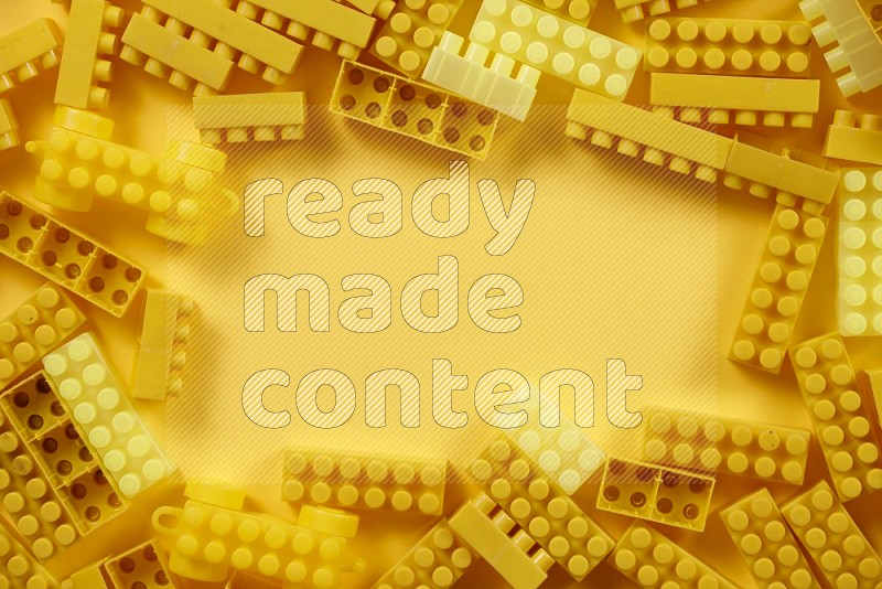 Yellow plastic building blocks on yellow background in top view (kids toys)
