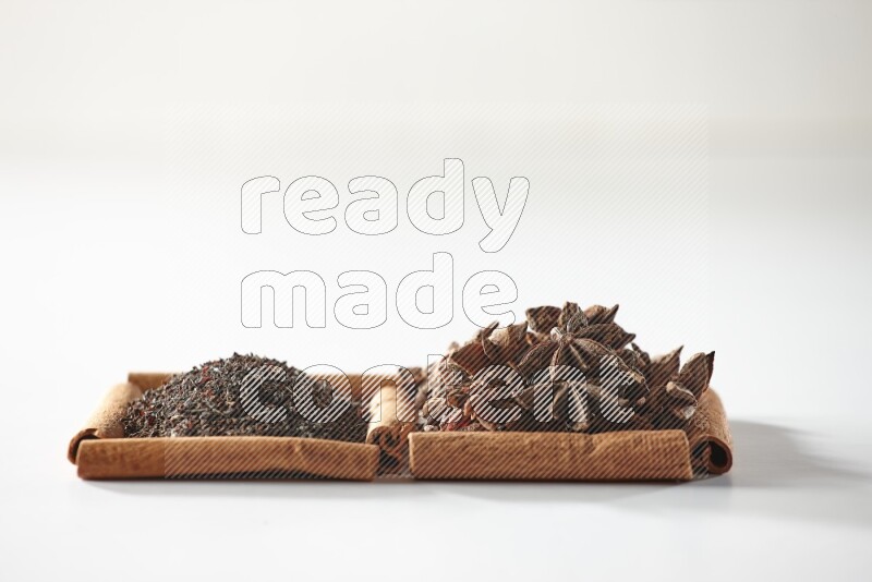 2 squares of cinnamon sticks full of star anise and black tea on white flooring