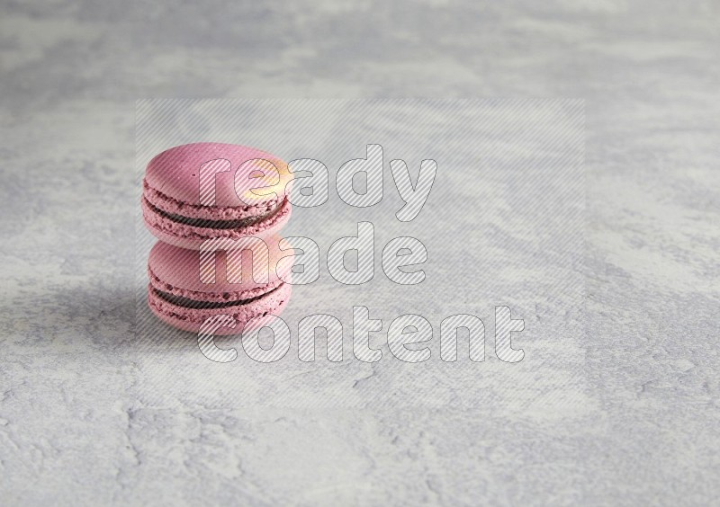 45º Shot of two Purple Strawberry macarons on white  marble background