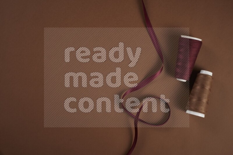 مجموعة من أدوات الخياطة والتفصيل حمراء اللون على خلفية بنية