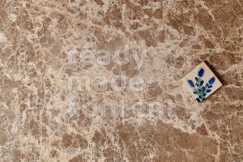 Top view shot of a pottery coaster tile on beige marble flooring