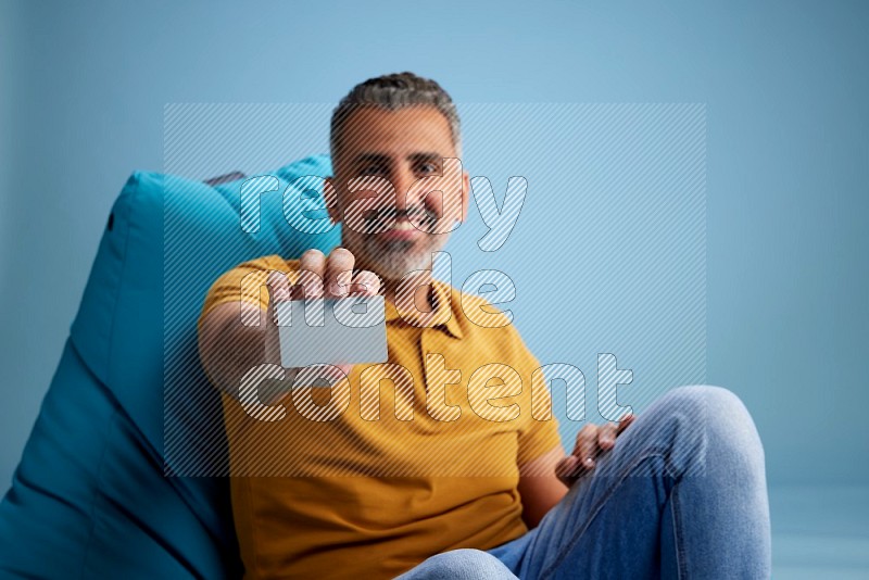 A man sitting on a blue beanbag and holding ATM card